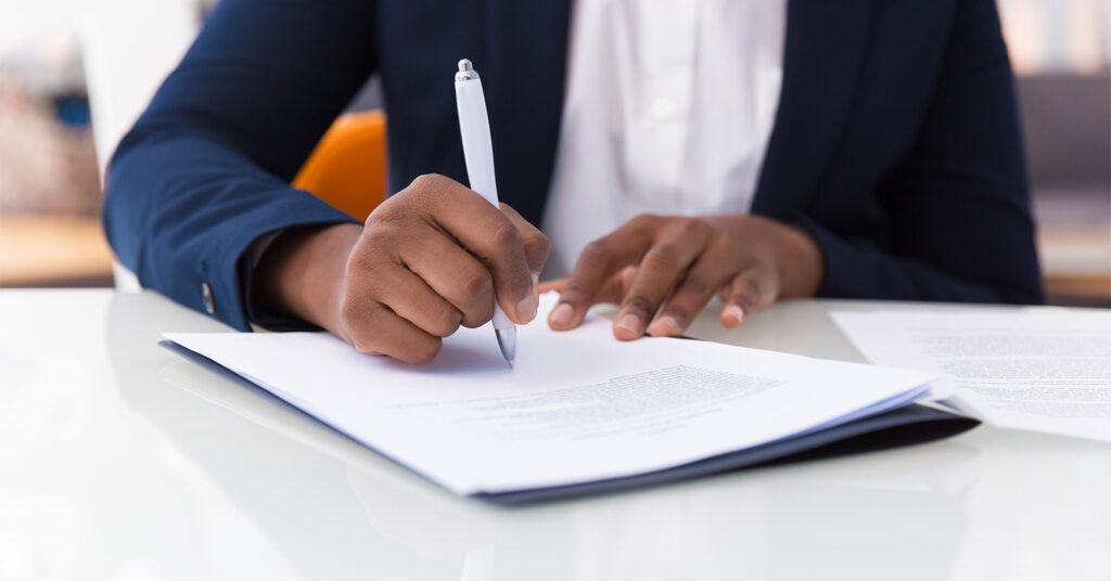 Businesswoman signing a government contract agreement during a meeting in an office.